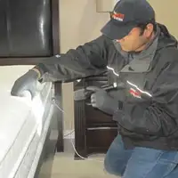 Bed bug inspection technician checking a mattress and bed frame for signs of infestation in Stockton, CA