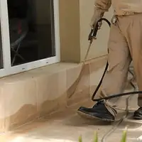 General pest control technician spraying exterior perimeter around a home in Stockton, CA