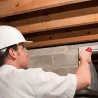 Termite inspection technician checking a basement wall and framing for termite activity in Stockton, CA