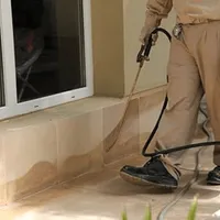General pest control technician spraying exterior perimeter around a home in Stockton, CA